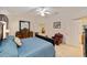 This bright main bedroom features carpeted floors, a comfy blue bed, and entry to another room at 2608 Casso Ct, The Villages, FL 32162