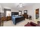 This main bedroom features a comfortable blue bed, dark furniture, a ceiling fan, and entry to an ensuite bathroom at 2608 Casso Ct, The Villages, FL 32162