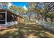 View of backyard featuring mature trees, grassy lawn, and white picket fence at 3299 County Road 521, Wildwood, FL 34785
