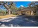View of the home and driveway with a carport, surrounded by mature trees and ample space at 3299 County Road 521, Wildwood, FL 34785