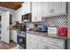 Charming kitchen with stainless steel appliances, granite countertops, white cabinets, and decorative backsplash at 3299 County Road 521, Wildwood, FL 34785