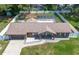 Aerial view of brick house with an attached garage, manicured lawn, fenced backyard and pool at 3881 Se 61St Pl, Ocala, FL 34480