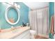 Bathroom featuring blue walls, a round mirror, and shower with curtain at 3881 Se 61St Pl, Ocala, FL 34480