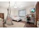 Cozy bedroom featuring a hanging chair, wood-look floors and a desk at 3881 Se 61St Pl, Ocala, FL 34480