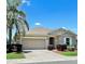 Charming one-story home with well-manicured landscaping, brick driveway, and attached two-car garage in a sunny neighborhood at 5009 Neptune Cir, Oxford, FL 34484