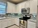 Modern kitchen with white cabinetry, stainless steel appliances, and stylish backsplash at 5009 Neptune Cir, Oxford, FL 34484