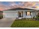 Charming single-story home featuring a two-car garage, landscaped garden, and inviting front porch at dusk at 8816 Sw 69Th Place Rd, Ocala, FL 34481