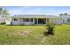 Rear exterior featuring a screened-in porch and a spacious grassy yard at 8849 Sw 116Th Place Rd, Ocala, FL 34481