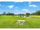Scenic view of a community pond with a charming white bench and expansive pasture land in the background at 8940 Sw 8Th St, Ocala, FL 34481