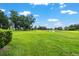 Expansive green yard with a pond and mature trees under a bright blue sky at 8940 Sw 8Th St, Ocala, FL 34481
