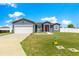 Inviting single-story home featuring a two-car garage, well-maintained lawn, and a red front door at 10291 Se 67Th Ter, Belleview, FL 34420