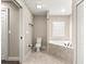 Bright bathroom featuring a tiled tub, tile flooring, and a neutral color scheme at 10313 Sw 45Th Ave, Ocala, FL 34476