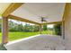 Covered outdoor patio with ceiling fan overlooking the expansive green backyard and serene surrounding landscape at 10313 Sw 45Th Ave, Ocala, FL 34476