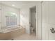 A bright, clean bathroom features a large soaking tub, a tiled floor, and a separate toilet room at 10716 Sw 53Rd Cir, Ocala, FL 34476