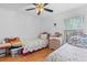Cozy bedroom features two twin beds, hardwood floors, a ceiling fan, and a large window for natural light at 10716 Sw 53Rd Cir, Ocala, FL 34476