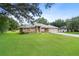Attractive single-story house featuring an arched doorway, gray roof, green lawn and long concrete driveway at 10716 Sw 53Rd Cir, Ocala, FL 34476