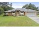 Charming single-story home featuring an arched entryway, well-maintained lawn, and attached two car garage at 10716 Sw 53Rd Cir, Ocala, FL 34476