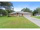 Lovely single-story home with an arched doorway, gray roof, lush green lawn and long concrete driveway at 10716 Sw 53Rd Cir, Ocala, FL 34476