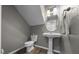 Cozy half-bathroom featuring a stylish pedestal sink, oval mirror, and toilet at 11521 Se 1St Street Rd, Silver Springs, FL 34488