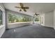 Enclosed sunroom with walls of windows, neutral carpeting, and ceiling fans overlooking the backyard at 11521 Se 1St Street Rd, Silver Springs, FL 34488