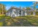 View of the side and back of the home, showing a gray exterior, covered patio, and well-maintained lawn at 12472 Se 67Th Terrace Rd, Belleview, FL 34420