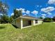 Backyard with a covered patio and green lawn under a blue sky with puffy white clouds at 13303 Sw 106Th Pl, Dunnellon, FL 34432