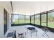 View of the screened porch with neutral concrete flooring, leading out to a large grassy backyard at 13561 Sw 85Th Pl, Dunnellon, FL 34432
