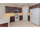 Kitchen features dark wood cabinets, white appliances, and light-colored tile floors at 1377 Sw 161St Pl, Ocala, FL 34473