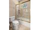A tiled shower and bathtub combination with a gold-trimmed sliding shower door and a window at 1675 Se 73Rd Pl, Ocala, FL 34480
