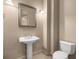 This half bath features a pedestal sink, a large mirror with decorative lighting, and a modern toilet at 1675 Se 73Rd Pl, Ocala, FL 34480