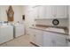 Bright laundry room with a utility sink, countertop space, ample cabinets, and modern washer and dryer at 2417 Se 23Rd St, Ocala, FL 34471