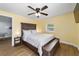 Cozy bedroom with yellow walls, wood-look floors, a ceiling fan, and a comfortable bed with an ottoman at 24628 Fox Rd, Astor, FL 32102
