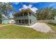 Two-story home featuring a screened-in porch, light green siding, and a gravel parking area at 24628 Fox Rd, Astor, FL 32102