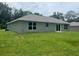 A modern, new backyard is defined by a grassy lawn and clean architectural lines; the sliding door opens to nature at 4105 Se 138Th Pl, Summerfield, FL 34491
