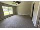 Spacious carpeted bedroom with a ceiling fan and a large window offering natural light at 4105 Se 138Th Pl, Summerfield, FL 34491