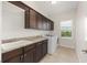 Well-lit laundry room with ample counter space, dark cabinetry, a utility sink and modern washer at 4360 Sw 62Nd Loop, Ocala, FL 34474