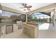 Outdoor kitchen with stainless steel grill, fridge, granite countertops, and screened in pool in the background at 4360 Sw 62Nd Loop, Ocala, FL 34474