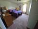 Comfortable bedroom features a large bed, soft carpet, dresser, and natural light from the window at 5130 Se 106 Lane, Belleview, FL 34420