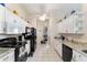 Efficient kitchen with white cabinets, black appliances, tile floors, granite countertops, and a ceiling fan at 5920 Sw 88Th Pl, Ocala, FL 34476
