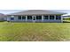 Rear exterior view featuring a bright sunroom with many windows and an expansive green lawn at 5920 Sw 88Th Pl, Ocala, FL 34476