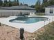 This backyard boasts a well-maintained in-ground pool and jacuzzi combo with a large white concrete patio at 6 Bahia Trace Loop, Ocala, FL 34472