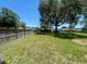 Wide view of the grassy backyard with mature trees and a wooden privacy fence at 6051 Ne 25Th Ave, Ocala, FL 34479
