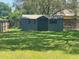A wooden shed with a dark-blue finish is surrounded by a large, grassy backyard at 6051 Ne 25Th Ave, Ocala, FL 34479