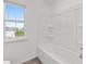 Bright bathroom featuring a white bathtub with shower and a window offering natural light at 7624 Sw 60Th St, Ocala, FL 34474