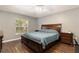 A spacious main bedroom has a king bed, wood flooring, and a large window with views of the yard at 8053 Sw 62Nd Ave, Ocala, FL 34476