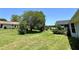 Expansive backyard featuring a lush green lawn, mature trees, and partial view of neighboring houses at 8239 Sw 108Th St, Ocala, FL 34481