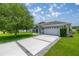 Home exterior featuring a long driveway and a two-car garage on a landscaped lawn at 11140 Sw 53Rd Cir, Ocala, FL 34476