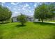 Well-maintained front yard with green grass and mature trees shading a home under a blue sky at 11140 Sw 53Rd Cir, Ocala, FL 34476