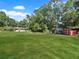 Wide shot of backyard with expansive lawn, home, and two storage sheds at 11230 Se 47Th Ave, Belleview, FL 34420