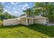 Side view of the home featuring a white exterior, fenced yard, and manicured lawn at 13314 Se 41St Ct, Belleview, FL 34420